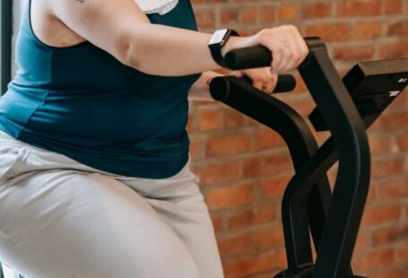 Crate Training - Side view of cheerful plus size ethnic female in activewear with towel exercising on fitness equipment during workout in gym