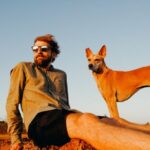 Basenji Dog - Photo of Man Sitting on Rock With His Dog