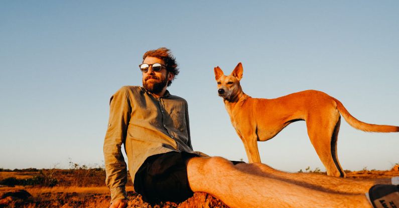 Basenji Dog - Photo of Man Sitting on Rock With His Dog
